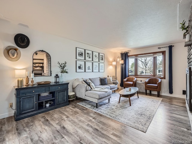 living room with a textured ceiling, baseboards, and wood finished floors