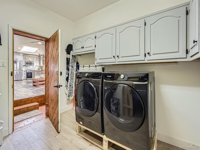 laundry room with cabinet space, baseboards, separate washer and dryer, and light wood-style floors