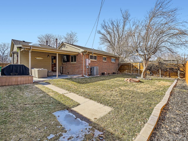 rear view of property with a fenced backyard, brick siding, an outdoor living space, a lawn, and a patio area