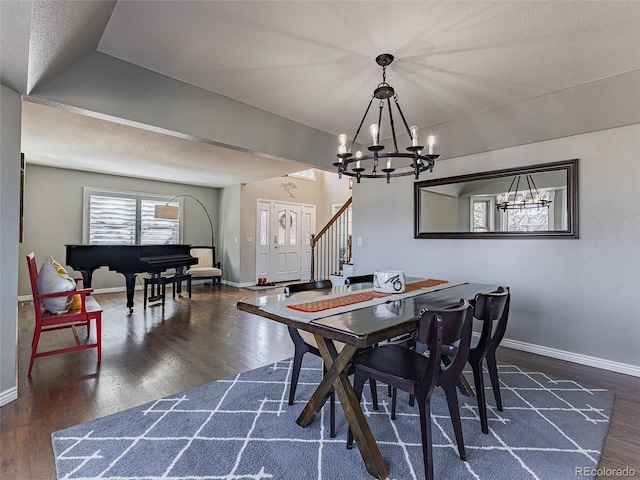 dining room featuring wood finished floors, a notable chandelier, baseboards, and stairs