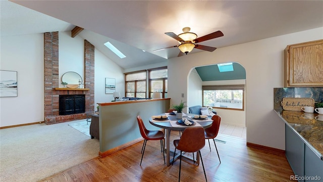 941 E 130th Cir, Thornton, CO 80241 - dining area with a skylight, ceiling fan, a brick fireplace, arched walkways, and beamed ceiling