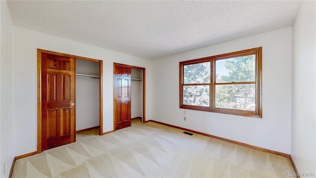 941 E 130th Cir, Thornton, CO 80241 - unfurnished bedroom featuring two closets, a textured ceiling, and light colored carpet
