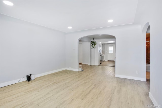 unfurnished room with light wood-type flooring, baseboards, arched walkways, and recessed lighting