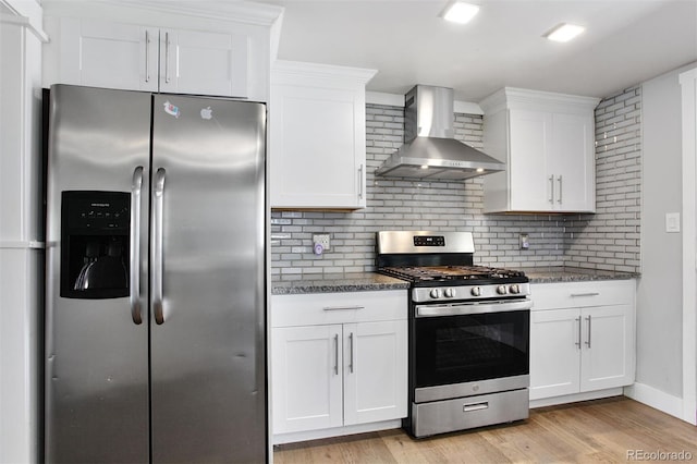 kitchen with white cabinets, stainless steel appliances, light wood-style flooring, backsplash, and wall chimney exhaust hood