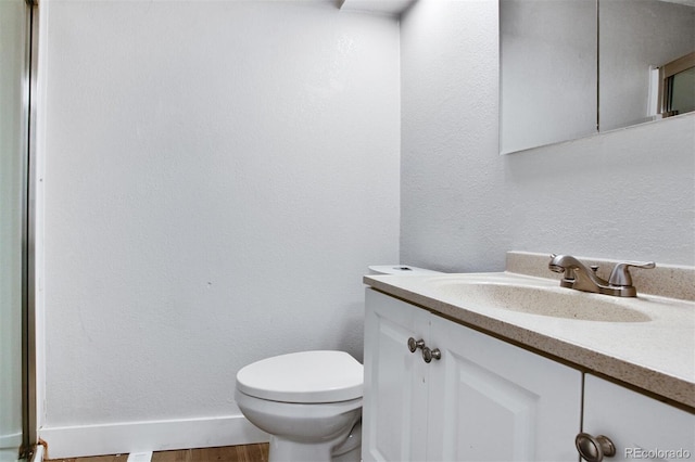 half bathroom featuring toilet, vanity, and wood finished floors