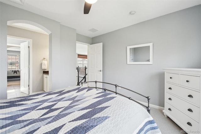 bedroom featuring multiple windows, light carpet, arched walkways, and baseboards