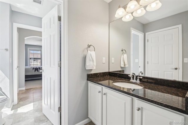 ensuite bathroom featuring vanity, tile patterned floors, baseboards, and toilet