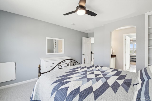 carpeted bedroom with arched walkways, a ceiling fan, and baseboards