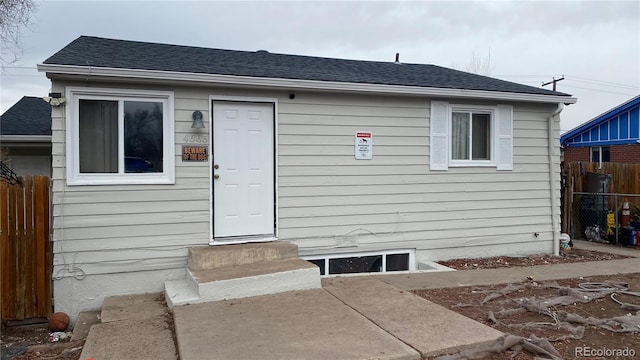 exterior space with a shingled roof, entry steps, and fence