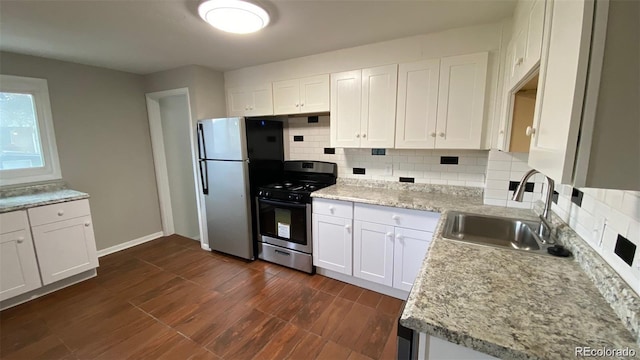 kitchen featuring gas range, dark wood-style flooring, freestanding refrigerator, white cabinetry, and a sink