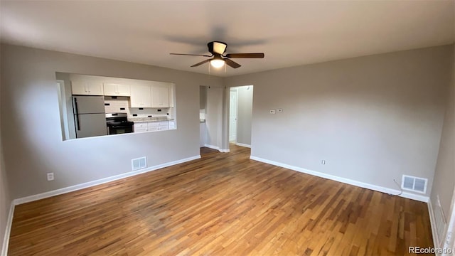 empty room featuring baseboards, visible vents, a ceiling fan, and wood finished floors