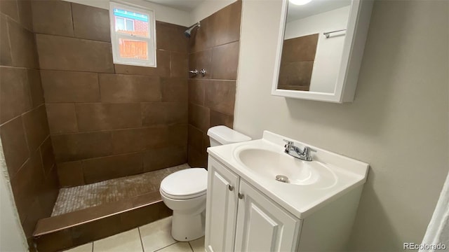 bathroom with vanity, a tile shower, toilet, and tile patterned floors