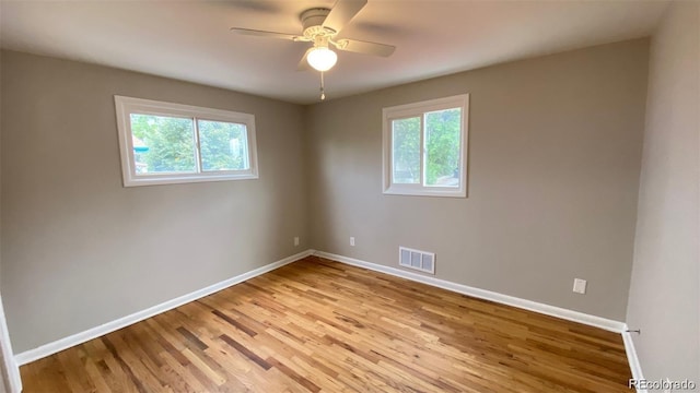 unfurnished room with light wood-style floors, a healthy amount of sunlight, visible vents, and baseboards