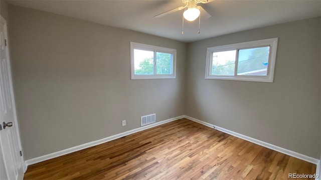 empty room with visible vents, ceiling fan, baseboards, and wood finished floors