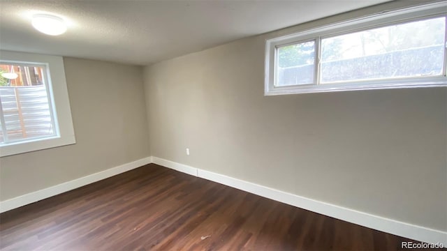 spare room with dark wood-style floors, a textured ceiling, and baseboards