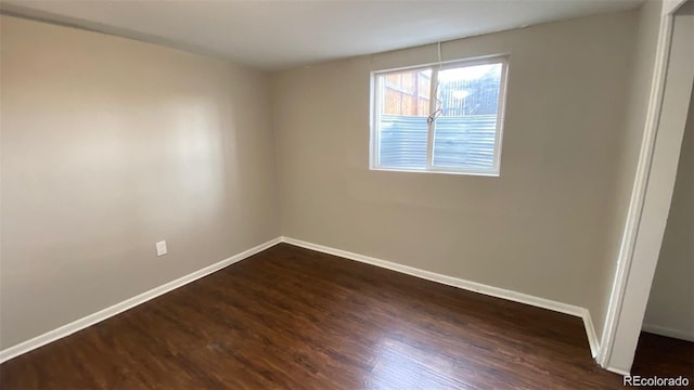 empty room with dark wood-type flooring and baseboards