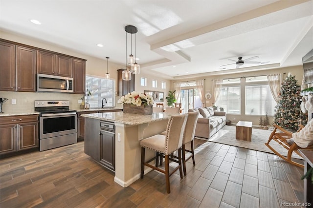 kitchen featuring ceiling fan, a center island, dark hardwood / wood-style floors, pendant lighting, and appliances with stainless steel finishes