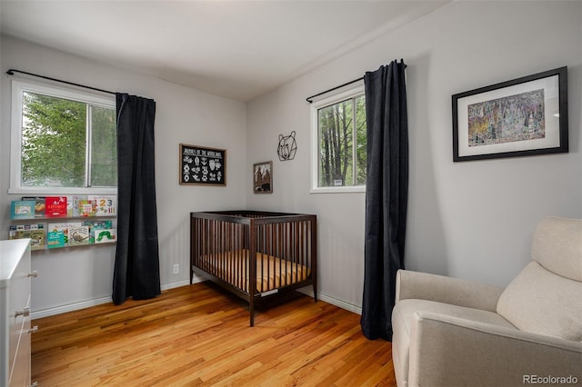 bedroom with light wood-type flooring and a nursery area