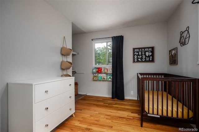 bedroom with a nursery area and light wood-type flooring