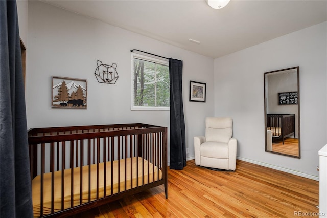 bedroom with light hardwood / wood-style floors and a nursery area