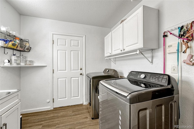 laundry area featuring cabinets, dark hardwood / wood-style floors, washing machine and dryer, and a textured ceiling