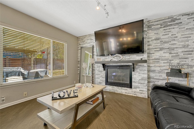 living room featuring a stone fireplace, dark hardwood / wood-style floors, and a textured ceiling