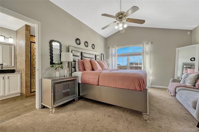 bedroom featuring light carpet, vaulted ceiling, ceiling fan, and ensuite bathroom