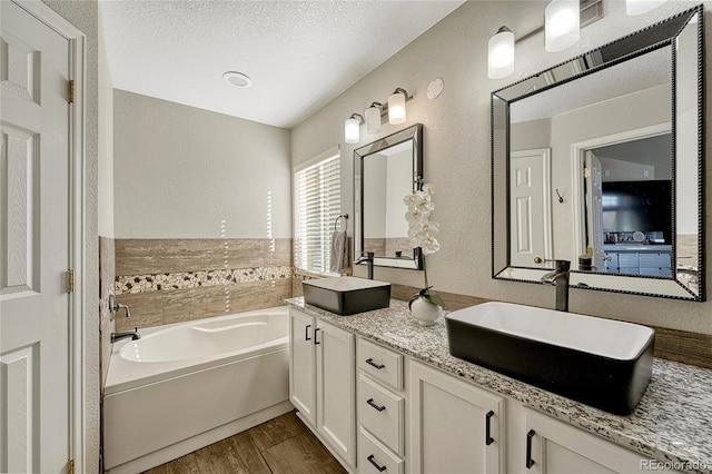 bathroom with vanity, hardwood / wood-style floors, a bathing tub, and a textured ceiling