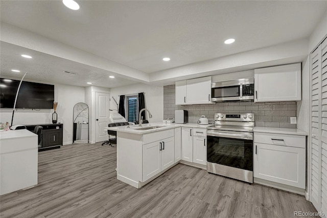 kitchen featuring stainless steel appliances, kitchen peninsula, sink, and white cabinets