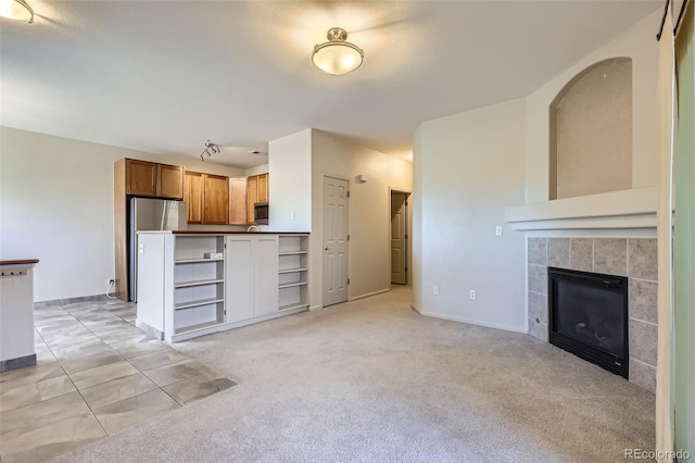 unfurnished living room with light carpet and a tile fireplace