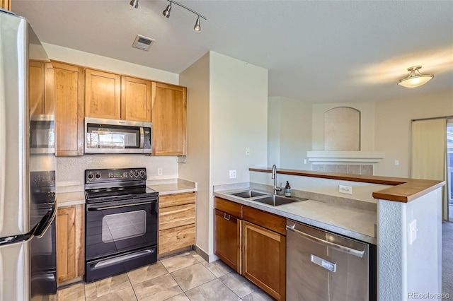 kitchen featuring kitchen peninsula, appliances with stainless steel finishes, sink, and light tile patterned flooring