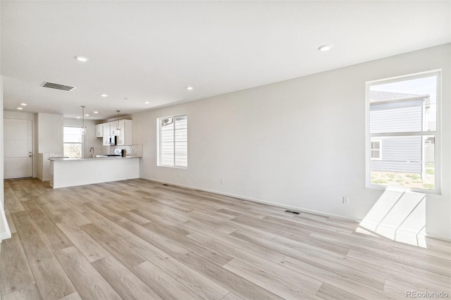 unfurnished living room featuring light wood-type flooring and sink