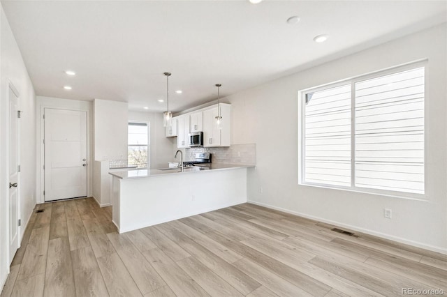 kitchen featuring kitchen peninsula, white cabinetry, light hardwood / wood-style flooring, and decorative light fixtures