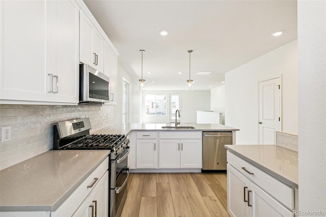 kitchen with light hardwood / wood-style floors, appliances with stainless steel finishes, sink, and white cabinetry