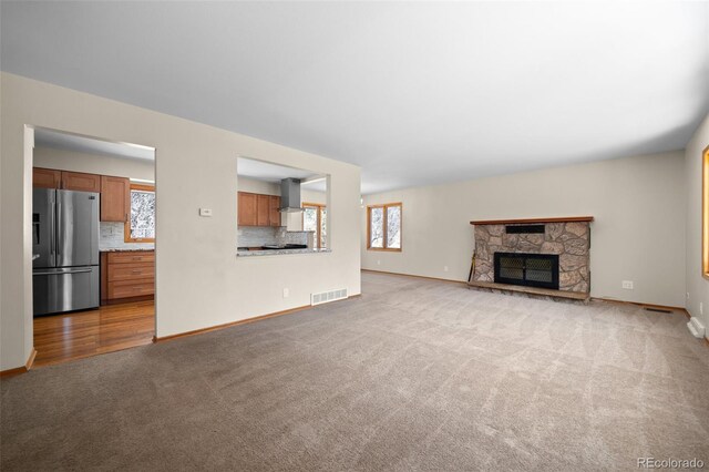 993 Fall River Rd, Idaho Springs, CO 80452 - unfurnished living room with carpet floors, a stone fireplace, visible vents, and baseboards