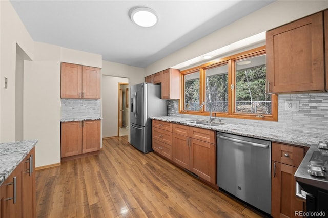 993 Fall River Rd, Idaho Springs, CO 80452 - kitchen featuring light stone counters, wood finished floors, a sink, decorative backsplash, and appliances with stainless steel finishes