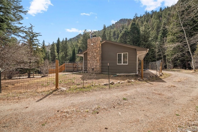 993 Fall River Rd, Idaho Springs, CO 80452 - view of property exterior featuring a chimney, fence, a view of trees, and a mountain view