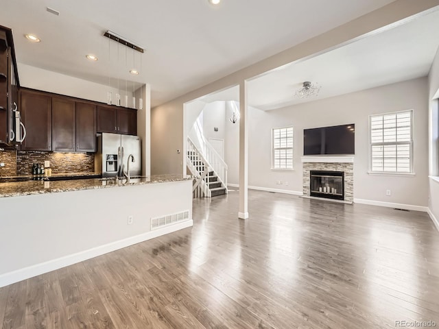 kitchen with dark brown cabinets, visible vents, light stone countertops, appliances with stainless steel finishes, and tasteful backsplash
