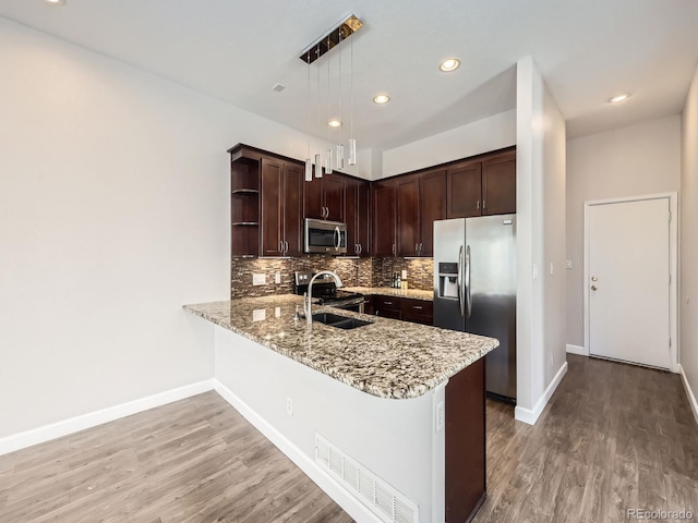 kitchen with appliances with stainless steel finishes, dark brown cabinets, light wood-style flooring, and light stone countertops