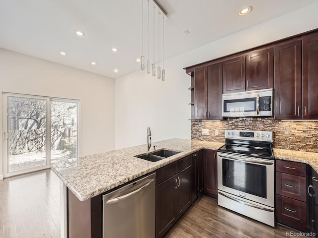 kitchen with a peninsula, decorative backsplash, stainless steel appliances, and a sink