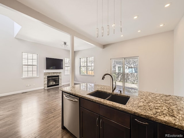 kitchen with a sink, dark wood-style floors, light stone counters, and dishwasher