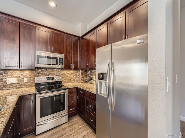 kitchen with light stone counters, stainless steel appliances, and tasteful backsplash