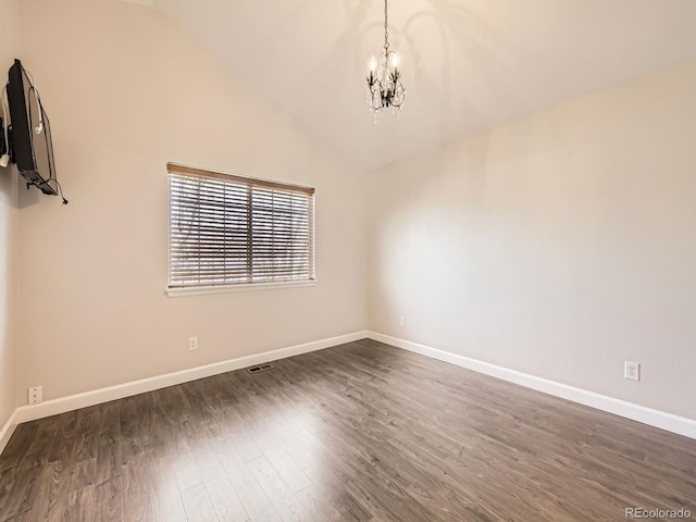 spare room with a chandelier, baseboards, lofted ceiling, and dark wood-style floors