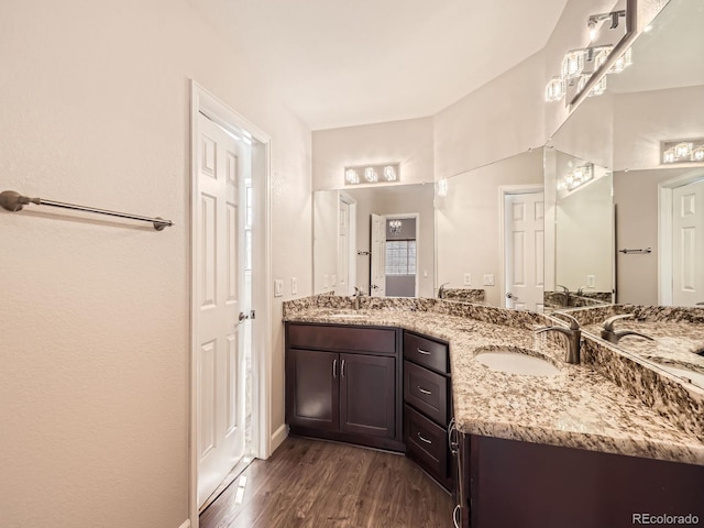 full bathroom with double vanity, wood finished floors, baseboards, and a sink