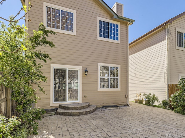 rear view of house with a chimney, a patio area, and fence