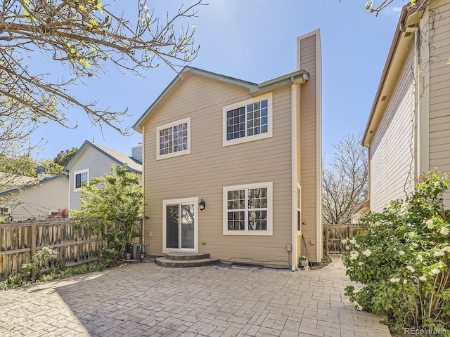 back of house featuring a chimney, a patio, a fenced backyard, and central AC