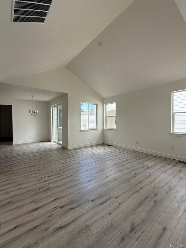 6113 Zebulon Pl, Timnath, CO 80547 - empty room with a chandelier, wood finished floors, vaulted ceiling, and baseboards