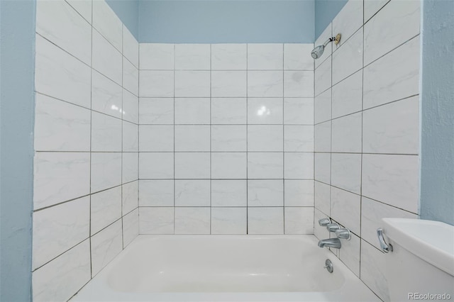 bathroom featuring tiled shower / bath and toilet