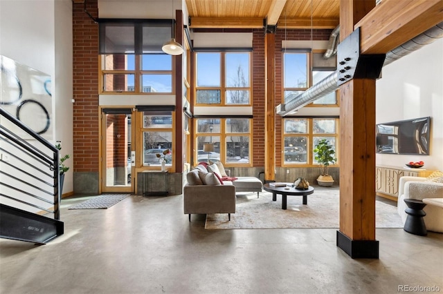 living room with wood ceiling, concrete flooring, beamed ceiling, and a high ceiling