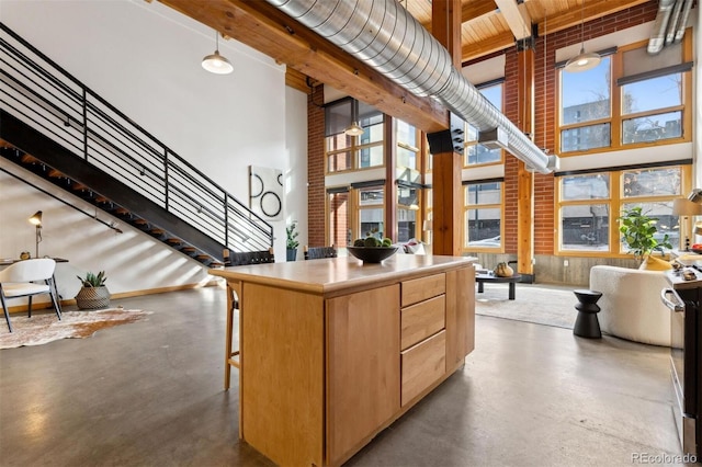 kitchen featuring a towering ceiling, light brown cabinets, beamed ceiling, and a kitchen island